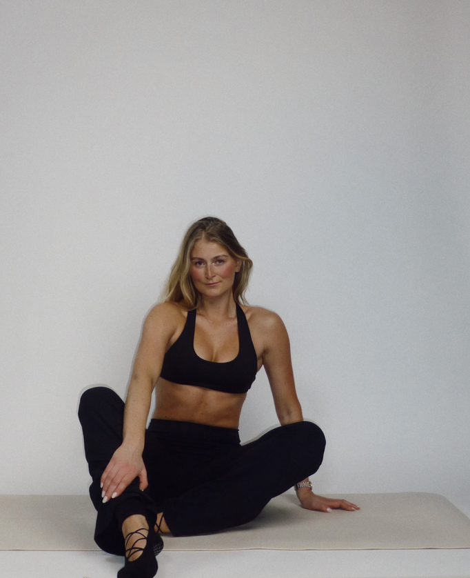 Wooden reformer and rolled mat in a dark studio with a shaft of daylight